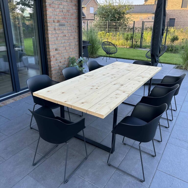 Gartentisch aus hellem Holz mit schwarzen Tischkufen und acht schwarzen Stühlen auf Terrasse