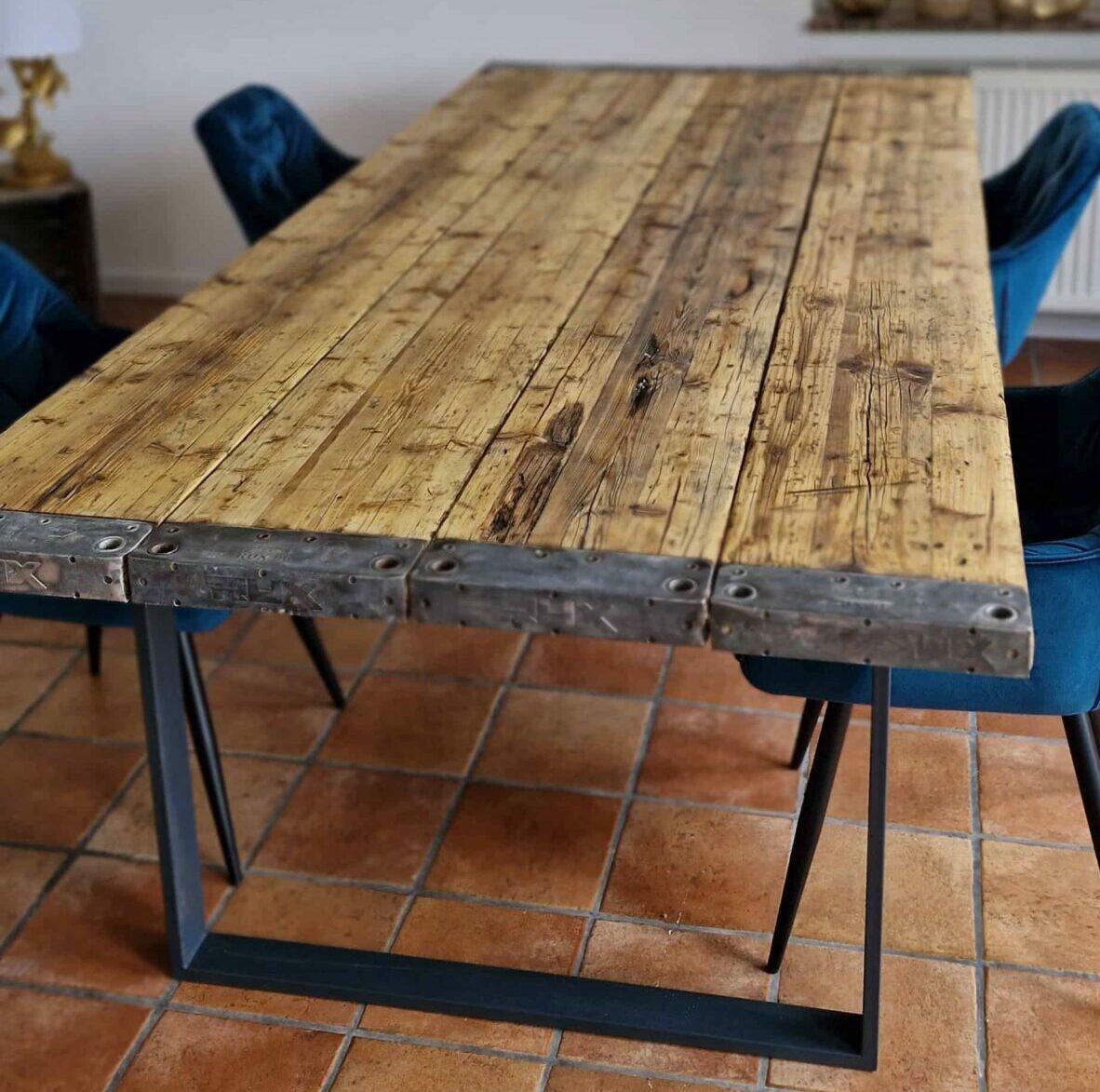 Großer Esstisch aus recyceltem Holz mit schwarzen Tischkufen und bunten Hängelampen im Esszimmer