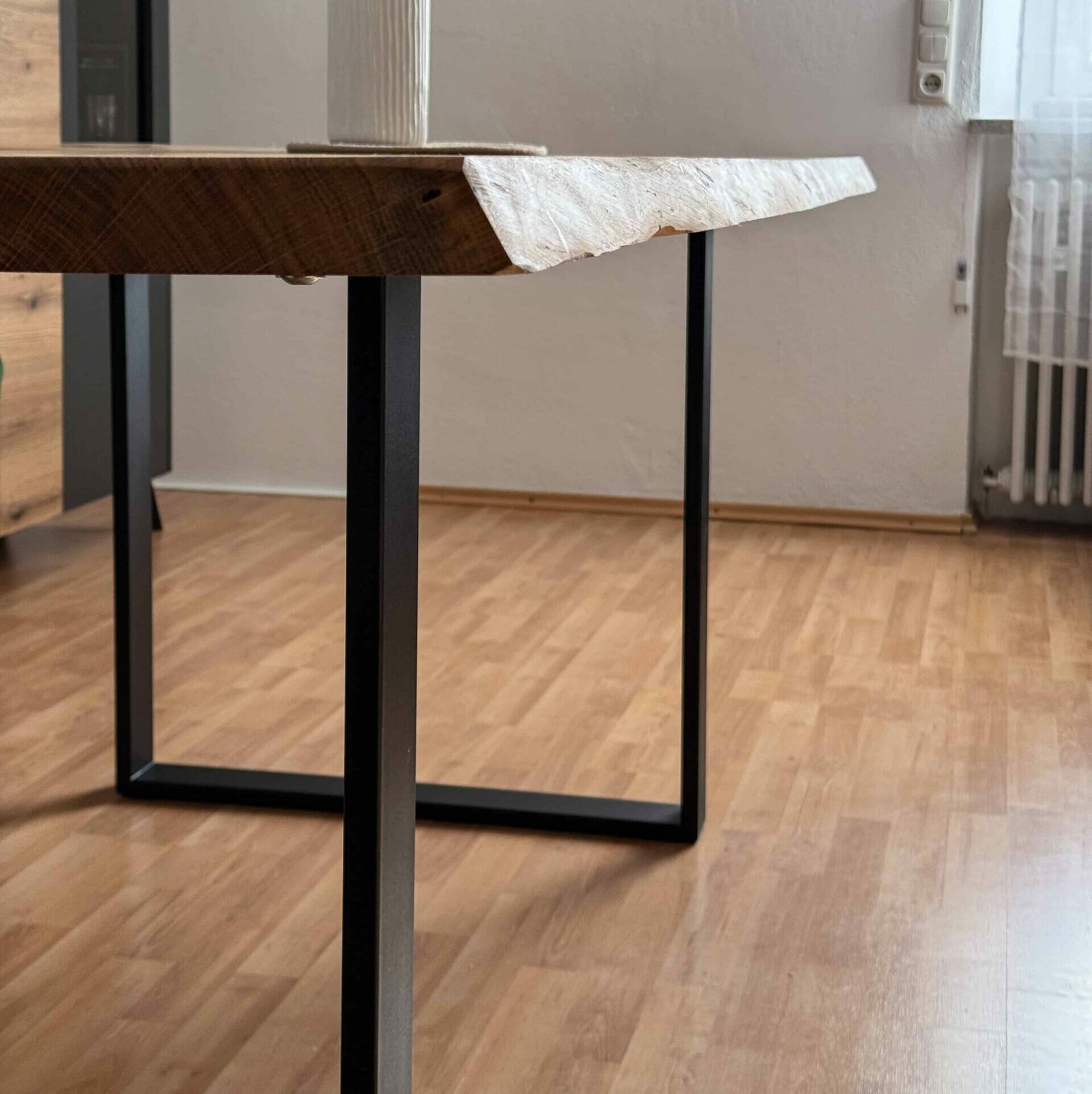 Massivholztisch mit schwarzem Kufengestell und naturbelassener Kante in modernem Wohnzimmer